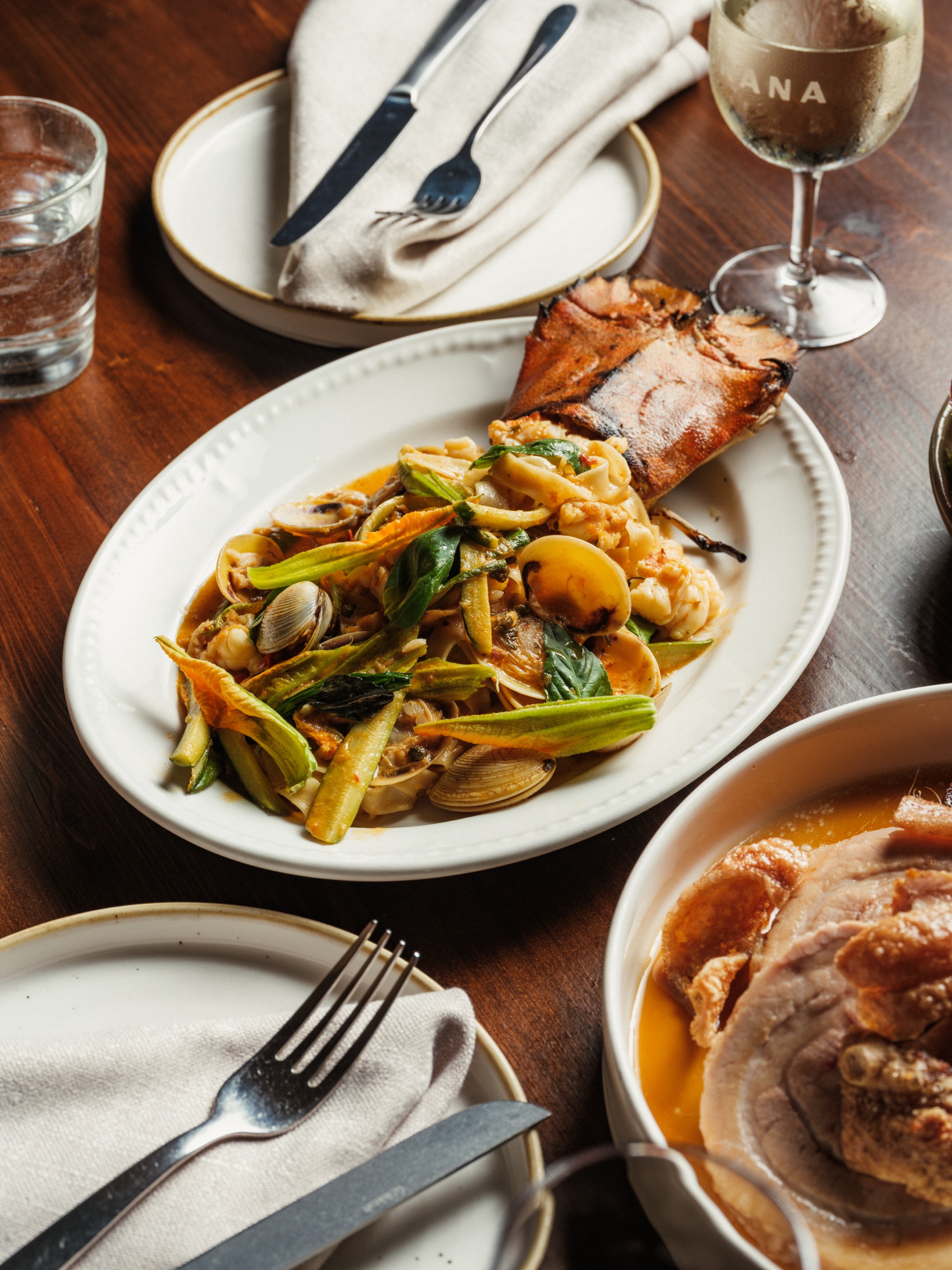 Shared pasta and seafood plates on a timber table at Grana